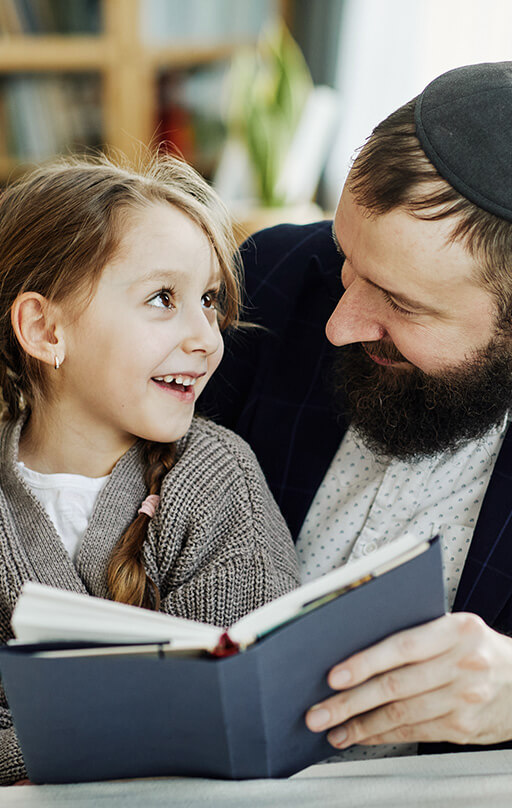 Smiling Jewish father reading book with daughter